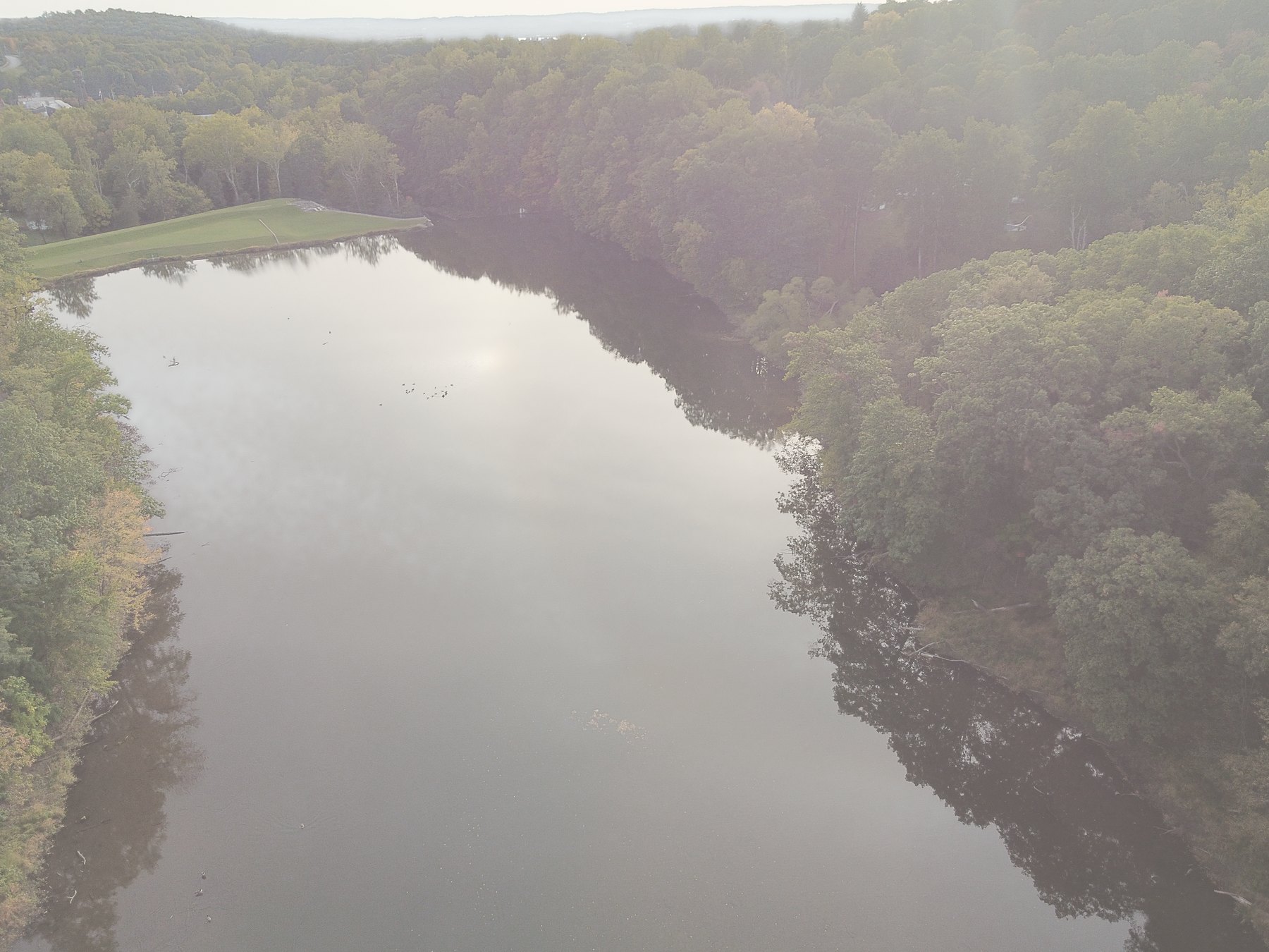 A broad, calm river with haze and light at the far shore